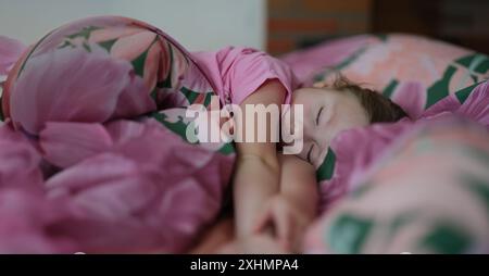 Portrait de petite fille enfant dormant doucement dans le lit. Sommeil diurne. Petit enfant au repos après une journée active. Concept de mode de vie sain Banque D'Images