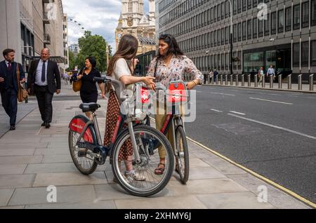 Londres / Royaume-Uni - 11 juillet 2024 : deux femmes avec des vélos électriques Santander près de la cathédrale de Westminster dans le centre de Londres, Royaume-Uni. Banque D'Images