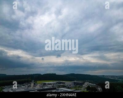 Centre commercial Massen, Wemperhardt , Weiswampach, Luxembourg, 30 juin, 2024, Une scène détaillée d'une zone industrielle sous un ciel couvert au milieu de collines ondulantes est capturée dans la vue panoramique Banque D'Images