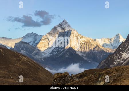 Montagne AMA Dablam au coucher du soleil et ciel bleu. Le soleil illumine les pentes. Montagnes de l'Himalaya, Népal. Banque D'Images