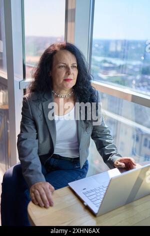 une femme de 57 ans travaille sur un ordinateur portable dans un espace de travail moderne Banque D'Images