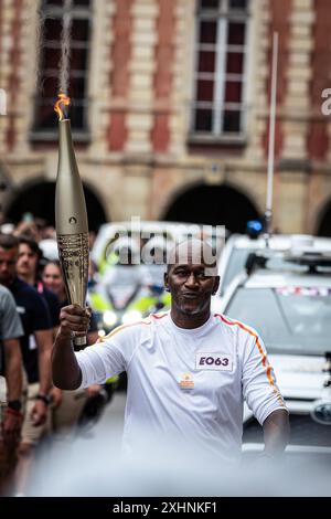 Paris, France. 14 juillet 2024. Un porte-flambeau olympique passe devant la Maison Victor Hugo sur la place des Vosges. Le jour des festivités de la Bastille, Paris a reçu la flamme olympique. Le premier des deux jours du voyage de la flamme olympique à Paris a commencé sur l'avenue des champs-Elysées, en passant par des sites emblématiques de la capitale française comme la cathédrale notre-Dame, et se terminant à l'Hôtel de ville. (Photo de Telmo Pinto/SOPA images/SIPA USA) crédit : SIPA USA/Alamy Live News Banque D'Images