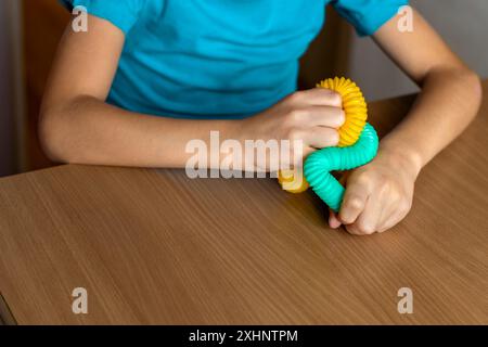 Jouets multicolores anti-stress à tube pop push Fidget pour enfants. Tuyau ondulé flexible dans les mains des enfants. gros plan. Soigner la santé mentale. Banque D'Images