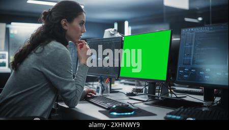 Développeur de logiciels femme travaillant sur un ordinateur de bureau avec écran vert maquette. Spécialiste de la saisie au clavier, du codage et de la mise en œuvre d'une nouvelle fonctionnalité technique, travaillant dans une agence Banque D'Images