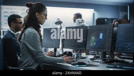 Jeune femme ingénieur en intelligence artificielle travaillant sur ordinateur dans un bureau technologique. Jeune spécialiste écrivant du code logiciel pour un projet de blockchain Big Data innovant. Photo vue de l'arrière Banque D'Images