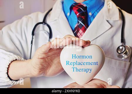 Médecin tenant un cœur avec le texte thérapie de remplacement hormonal - forme de thérapie hormonale utilisée pour traiter les symptômes associés à la ménopause féminine, AC Banque D'Images