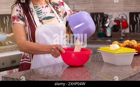 concepts de ménage et de style de vie. gros plan des mains d'une femme mélangeant des ingrédients dans un récipient. femme au foyer dans une cuisine complète. Banque D'Images