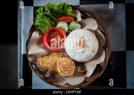 Riz au poulet frit et tempeh avec des légumes verts de moutarde et sauce Chili sur une assiette en rotin, prêt à manger Banque D'Images