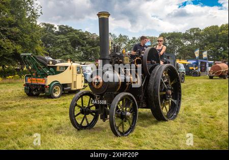 Storrington / Royaume-Uni - 13 juillet 2024 : une jeune femme conduit un moteur de traction à vapeur Wallis & Steevens 1915 à Sussex Steam Fair, Parham, Storrington, Royaume-Uni. Banque D'Images