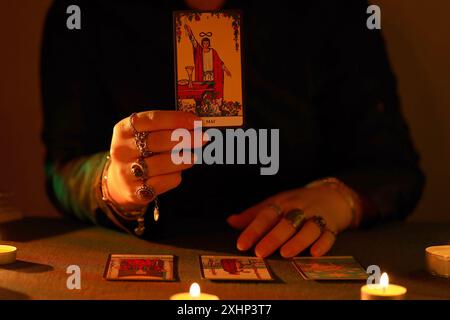 KIEV, UKRAINE - 10 JUILLET 2024 lecteur de tarot cueillant des cartes de tarot. Chandelles dans une pièce sombre. Lecture de tarot et prévision de gros plan sur le lecteur de tarot ou le caissier Banque D'Images