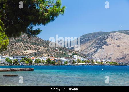 Vue panoramique d'Antikyra, Béotie, Grèce, avec front de mer pittoresque, verdure luxuriante, et des collines ondulantes sous un ciel bleu vif. Banque D'Images