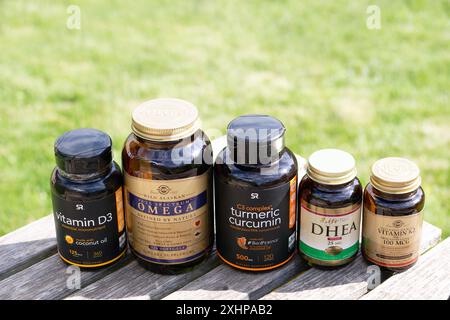 Nijni Novgorod, Russie, juillet 2023. Compléments alimentaires et vitamines dans des bouteilles de différents fabricants sur fond d'herbe verte Banque D'Images