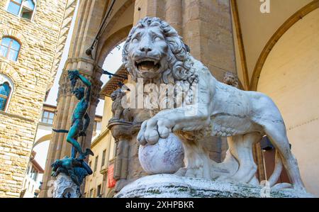 Un des Lions de Médicis avec Persée avec la tête de Méduse en arrière-plan. Piazza della Signoria, Florence, Toscane, Italie. Banque D'Images