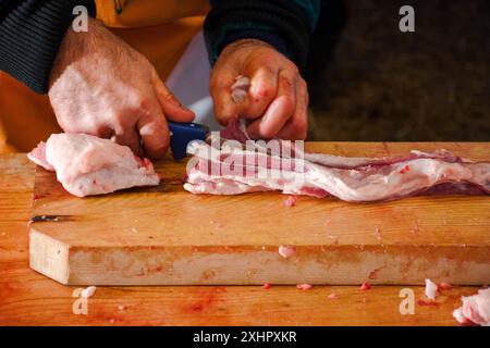 boucher coupant la viande crue sur le bureau en bois. procédé de préparation de graisse de porc Banque D'Images