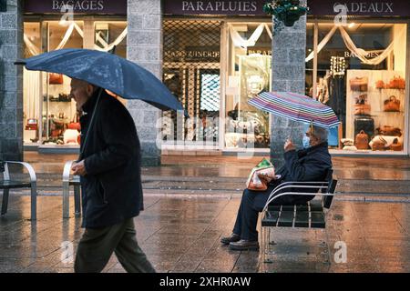 France, Finistère, Brest, deux hommes prennent refuge sous leur parapluie sur la place Monseigneur Roul devant un magasin de parapluie Banque D'Images