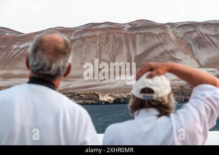 Paracas, Pérou - 19 mars 2019 : les touristes observent l'ancien géoglyphe Candelabro de Paracas sur une colline sablonneuse. Banque D'Images