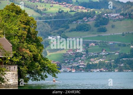 Un homme rame un bateau sur un lac près d'une ville. Le lac est entouré d'arbres et de maisons. La scène est paisible et sereine, avec l'homme appréciant le Banque D'Images