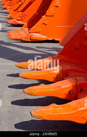 Groupe de pelles oranges d'excavatrice, plan de perspective décroissant, fond abstrait de l'industrie de la construction Banque D'Images