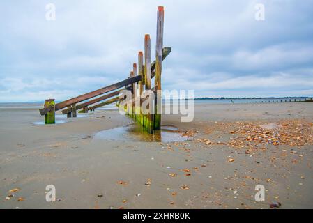 Une vue basse sur West Wittering UK Beach à travers les groynes en bois altérés par les intempéries Banque D'Images