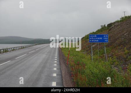 Route de campagne solitaire sous ciel nuageux avec panneau indiquant Lulea et Kiruna, automne en Laponie, Tornetraesk, Abisko, Suède Banque D'Images