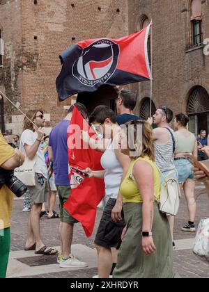 Foule tenant des drapeaux de protestation près d'un mur de briques, s'engageant dans la conversation, éditorial gay Pride cremona italie 6 juillet 2024 Banque D'Images