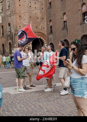 Les gens se sont rassemblés lors d'une manifestation avec des drapeaux près d'un bâtiment en briques, certains regardant leurs téléphones, éditorial gay Pride cremona italie 6 juillet 2024 Banque D'Images