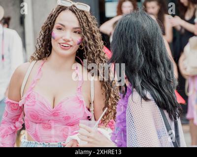 Deux femmes, dont une vêtue de rose, parlant joyeusement pendant un festival, éditoriale gay Pride cremona italie 6 juillet 2024 Banque D'Images