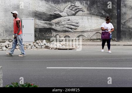 Deux personnes passent devant un mur avec une grande murale, Cuba, les grandes Antilles, les Caraïbes, l'Amérique centrale, Amérique Banque D'Images