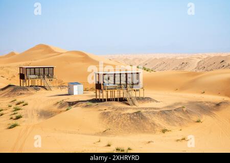 Des maisons d'hôtel du désert debout au-dessus du sable au milieu du désert de Wahiba, Oman Banque D'Images