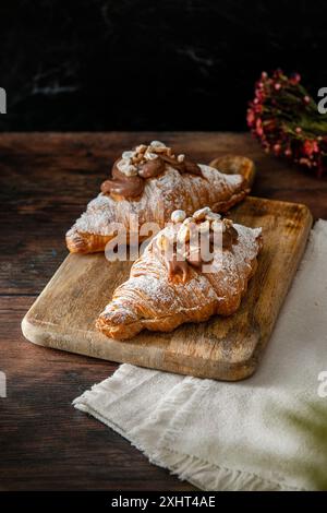 Croissants au chocolat gastronomique fraîchement cuits sur un fond en bois. Banque D'Images