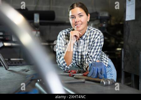 Jeune femme posant dans un atelier métallurgique Banque D'Images