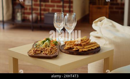 Plateau de charcuterie et plateau de fromage gastronomique mis en place par les hôtes pour accueillir correctement les invités arrivant bientôt à la fête de l'appartement. Verres à vin à côté des collations dans le salon mur de briques Banque D'Images