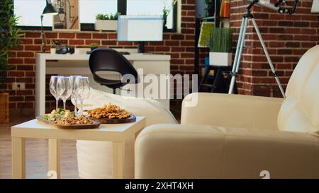 Vide élégant appartement confortable salon avec des craquelins, des cacahuètes et du fromage sur panneau de charcuterie, en attente des invités pour arriver pour l'événement social. Intérieur élégant de la maison avec ambiance chaleureuse, de près Banque D'Images