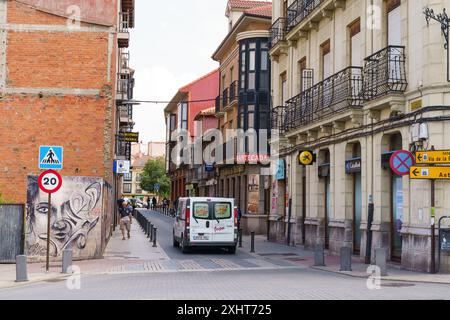 Astorga, Espagne - 3 juin 2023 : une camionnette blanche traverse une rue étroite d'Astorga, Espagne, devant un bâtiment en briques rouges et un panneau indiquant un piéton Banque D'Images