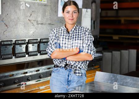 Jeune femme posant dans un atelier métallurgique Banque D'Images