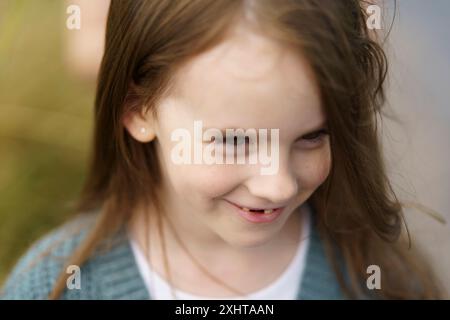 Mignonne belle petite fille aux cheveux roux sans dents sur le fond d'un champ de blé et d'une route rurale. Concept de voyage pour enfants Banque D'Images