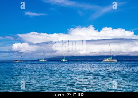 Quatre bateaux sont ancrés au large de Maui, Hawaï. Une grande formation de nuages en forme de disque entre en éruption de l'île voisine. Photo de haute qualité Banque D'Images