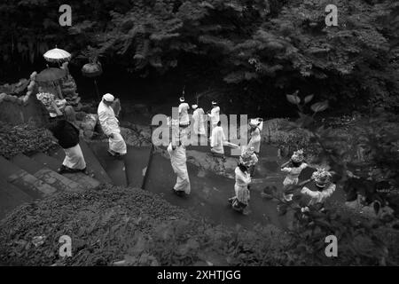 Purifier les esprits : les membres d'une famille balinaise marchent en ligne pendant un rituel, portant des seaux d'offrandes à Karangasem, Bali, Indonésie. Banque D'Images