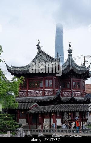 Shanghai, Chine - 06 juin 2024 : Un pavillon chinois traditionnel avec des sculptures complexes, entouré de verdure et d'un pont de pierre. En arrière-plan Banque D'Images