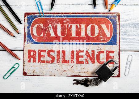 Résilience. Plaque de CAOTION en métal avec texte sur un fond en bois blanc. Banque D'Images