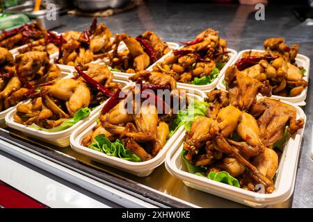 Marché nocturne asiatique traditionnel avec nourriture exotique pour les touristes. Grenouilles marinées sur le comptoir d'un restaurant de rue pour griller. Photo de nuit sous fluores Banque D'Images