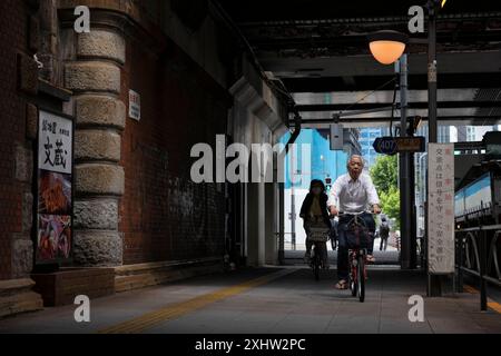 Tokyo, Japon. 23 mai 2024. Un senior japonais monte son vélo sous un pont de chemin de fer près de la gare de Tokyo le 23 mai 2024. - 20240523 PD30150 crédit : APA-PictureDesk/Alamy Live News Banque D'Images