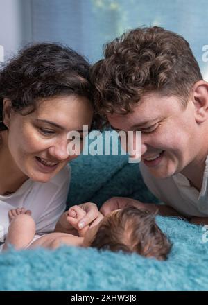 Famille heureuse avec un nouveau-né. Une mère et un père amoureux tiennent doucement leur bébé fils dans leurs bras et regardent tendrement l'enfant. Banque D'Images