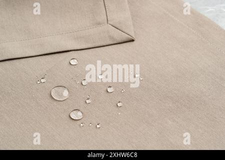 Gros plan des gouttelettes d'eau sur la surface en tissu beige Banque D'Images