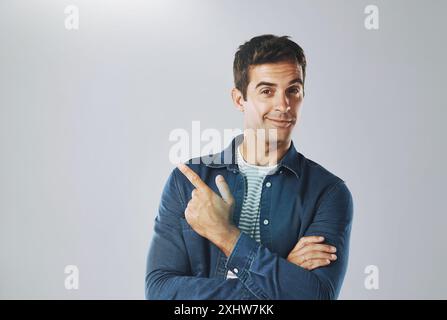 Portrait, pointage et homme avec revue, opportunité et modèle sur fond gris de studio. Visage, personne et gars avec geste de la main, espace maquette et Banque D'Images