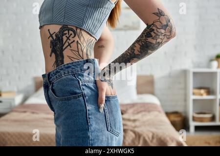 Une jeune femme avec des tatouages se détend dans son appartement moderne lors d'un week-end confortable. Banque D'Images