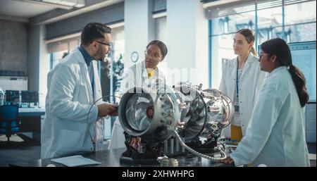 Équipe d'ingénieurs industriels travaillant sur un moteur à réaction futuriste, discutant dans le laboratoire de technologie scientifique. Divers jeunes scientifiques développant un nouveau moteur électrique dans une installation de recherche Banque D'Images
