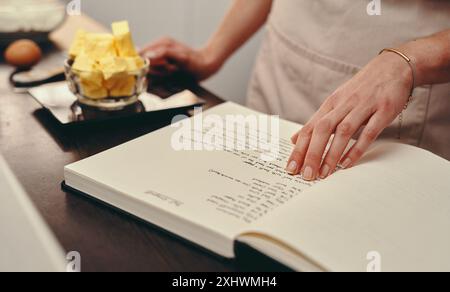 Mains, personne ou livre de lecture pour recette de méthode de cuisson, dîner ou guide secret à la maison. Gros plan, instruction et chef avec cahier pour le menu Banque D'Images