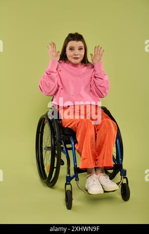 Une jeune femme brune en fauteuil roulant est assise dans un studio. Elle porte des vêtements décontractés et a une expression surprise sur son visage. Banque D'Images