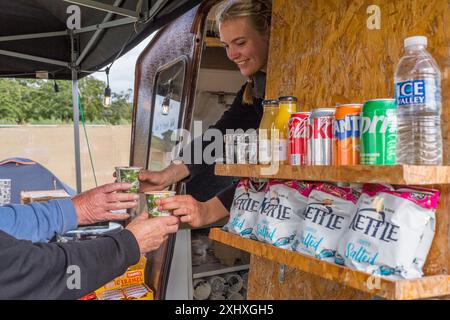 Les gens qui sont servis des boissons et de la nourriture dans un pop up shop à un festival de musique en plein air. Banque D'Images